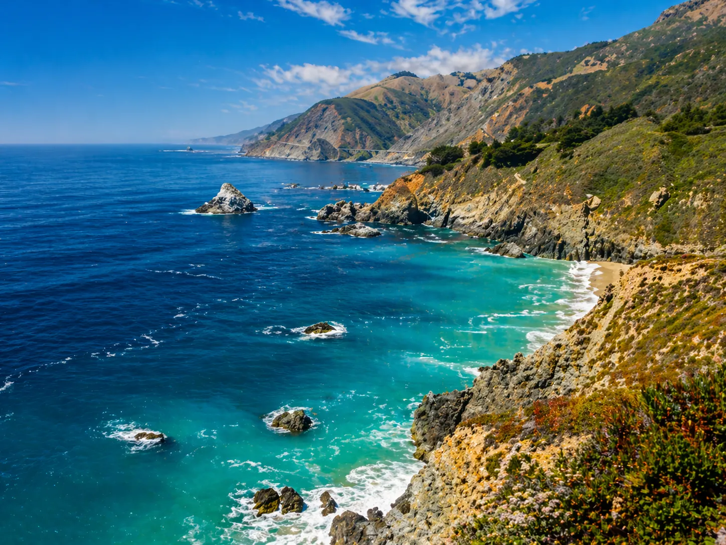 A vivid coastline scene with blue water and rugged cliffs